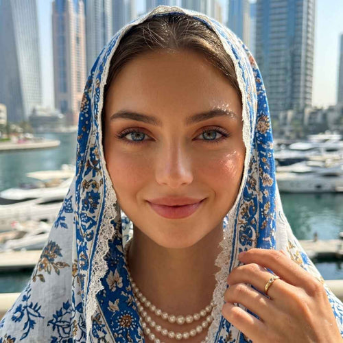 Woman wearing a blue and white patterned headscarf with a cityscape and waterfront in the background
