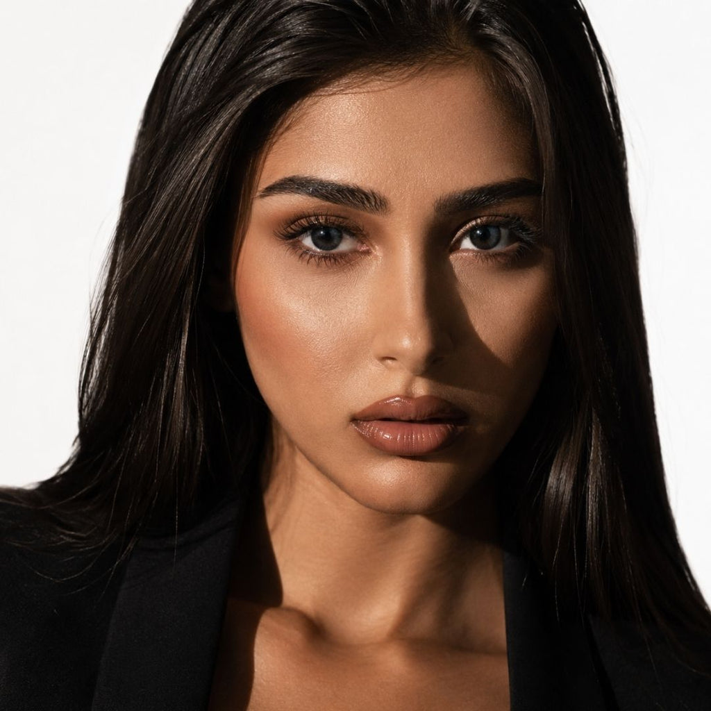 Studio portrait of a woman with long dark hair wearing mystery black contact lenses that create a cool smoky eye appearance. Soft lighting and neutral makeup keep the focus on the eyes.

