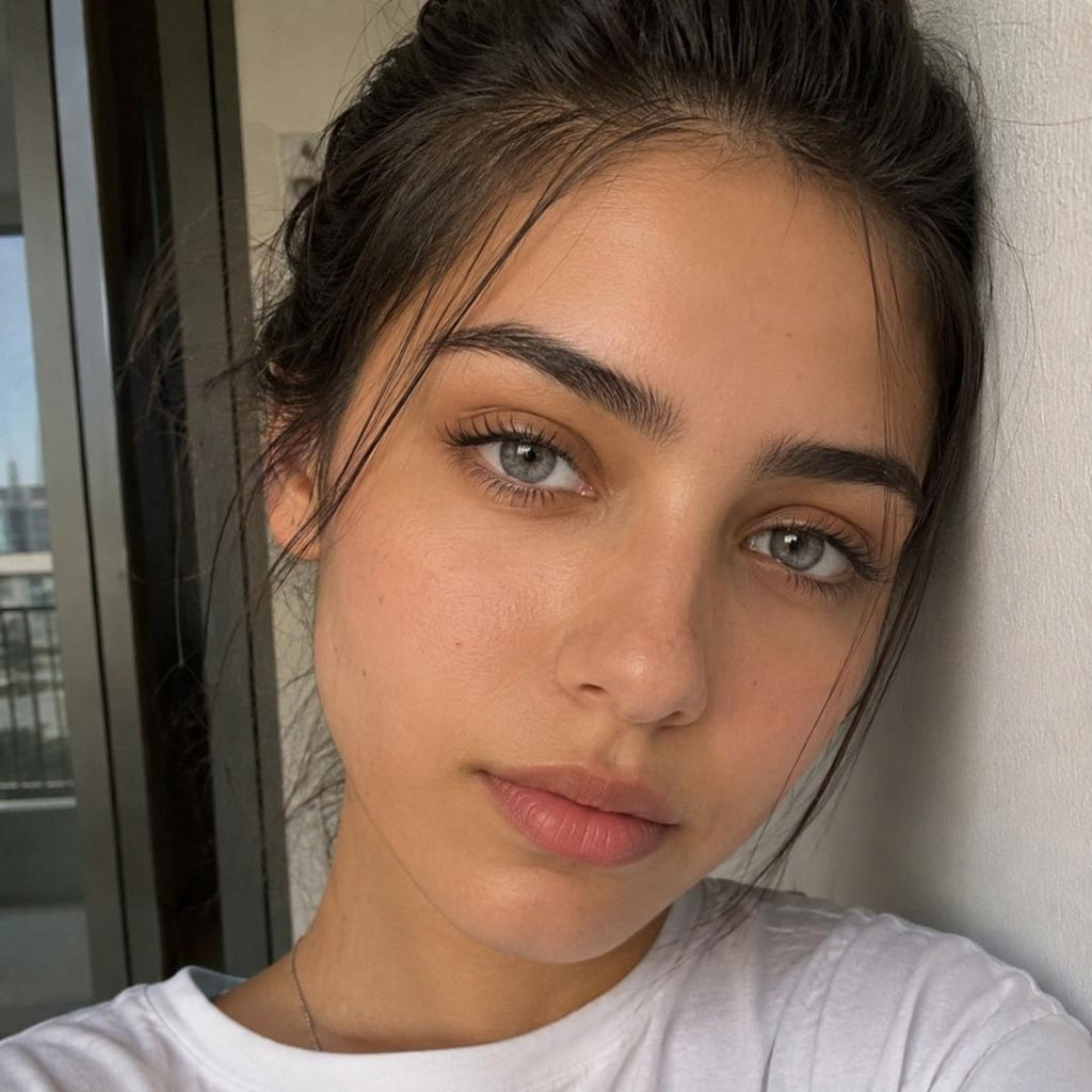 Woman with light makeup and gray color lens leaning against a wall indoors