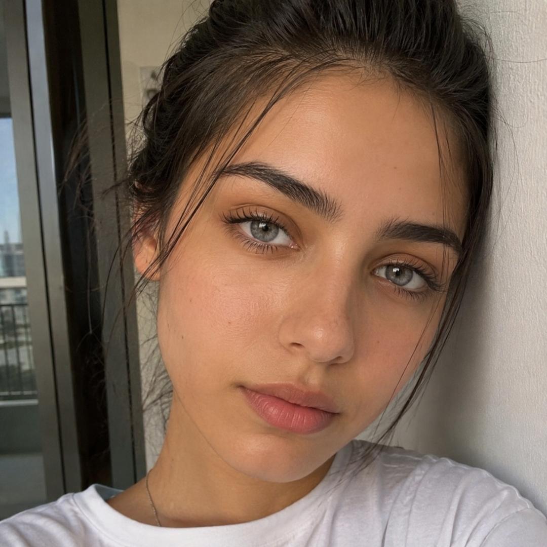 Woman with light makeup and gray color lens leaning against a wall indoors