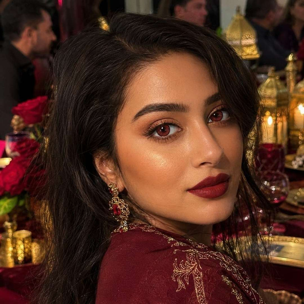 Woman with dark hair and red lipstick look at camera with crimson red eyes