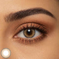 Detailed close up of an eye wearing subtle brown colored contacts with a soft hazel brown center and darker outer ring. Warm bronze eyeshadow and long lashes enhance the natural looking lens color.