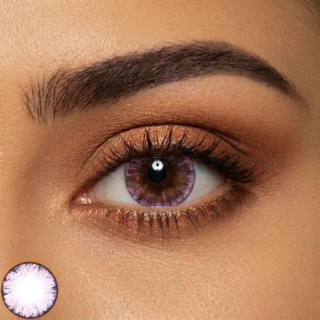 Close up of one eye wearing a pink lens for dark eyes, showing a lavender pink pattern around the iris and a defined limbal ring. The comparison inset highlights the lens design and color detail.