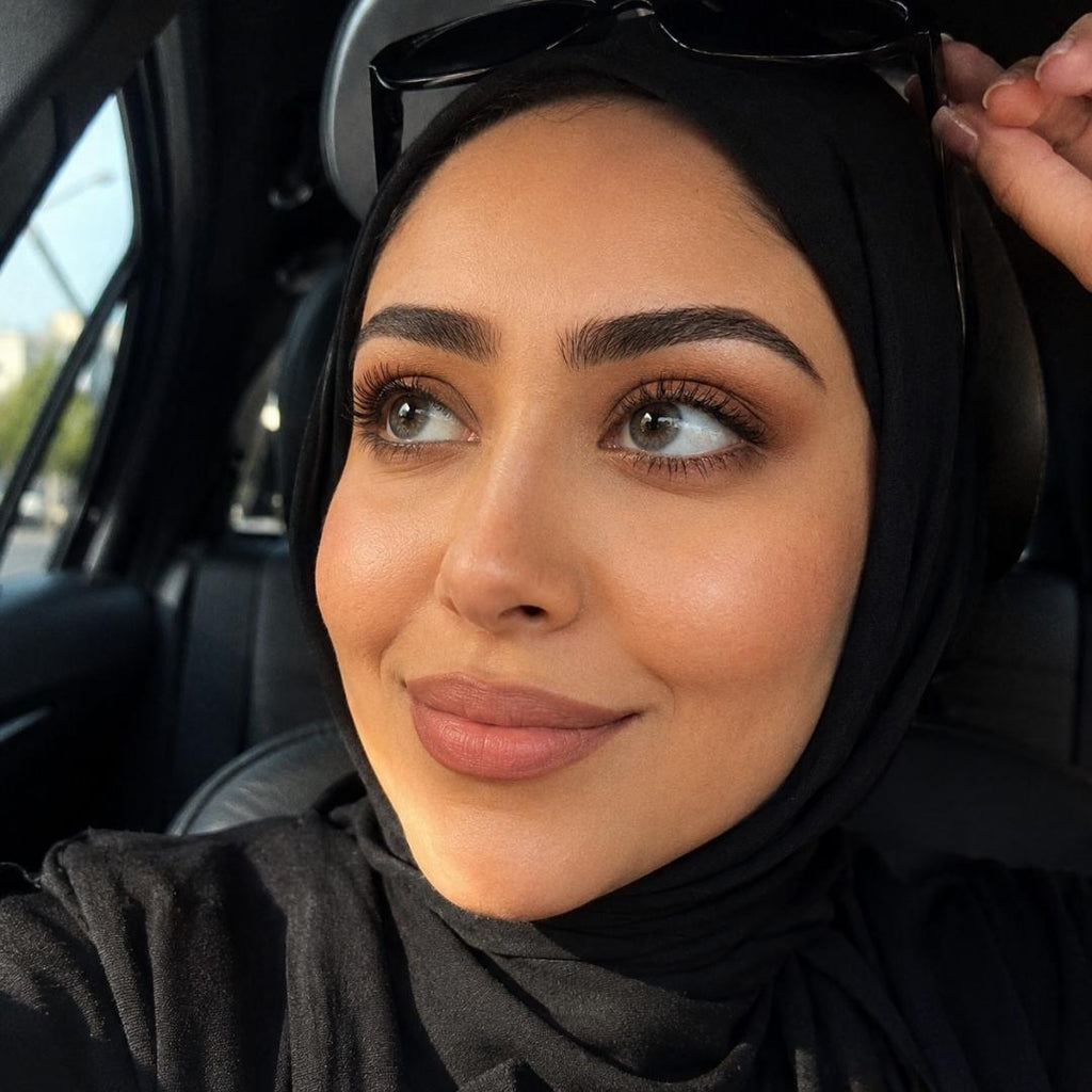 Woman wearing a black hijab sitting inside a car.