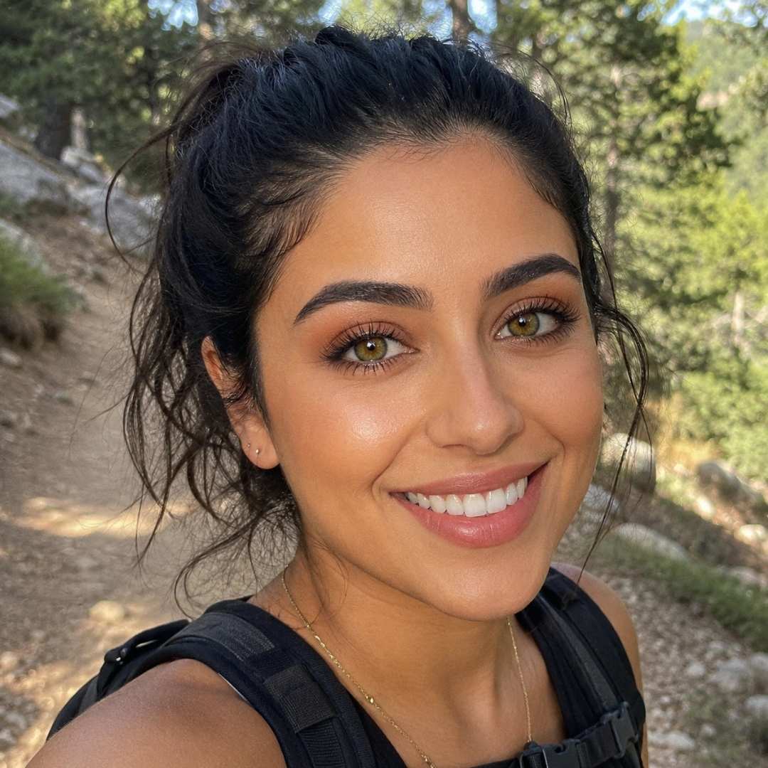 Woman with a backpack smiling outdoors in a natural setting