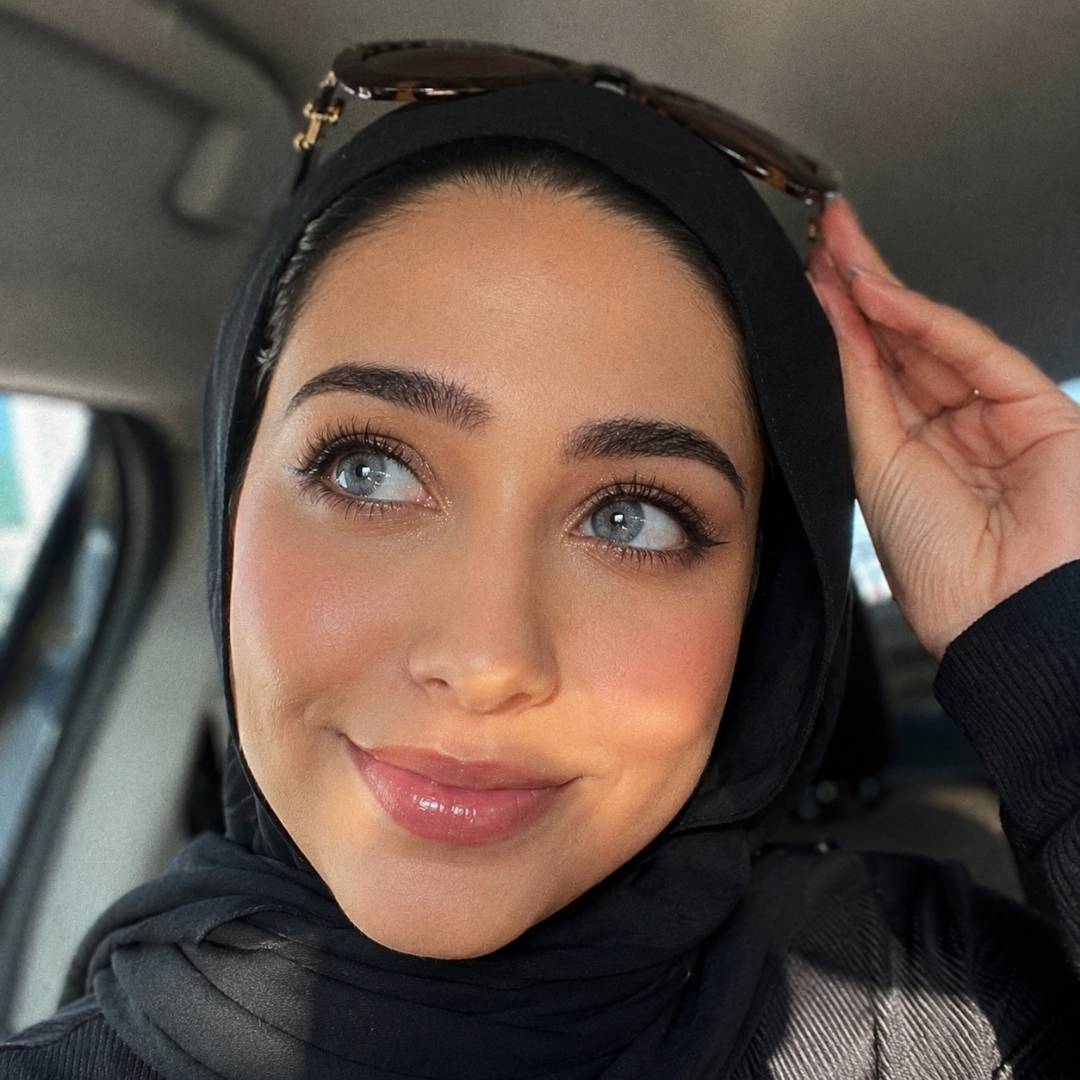 A woman in a black hijab and sunglasses, showcasing striking coco gray contact lenses in her car