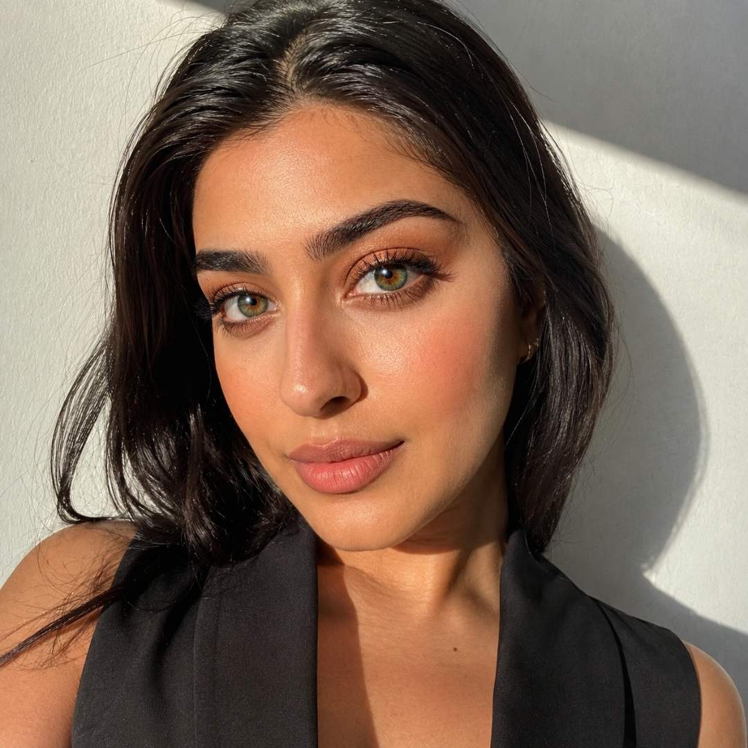 Woman with dark hair and green eyes against a light background