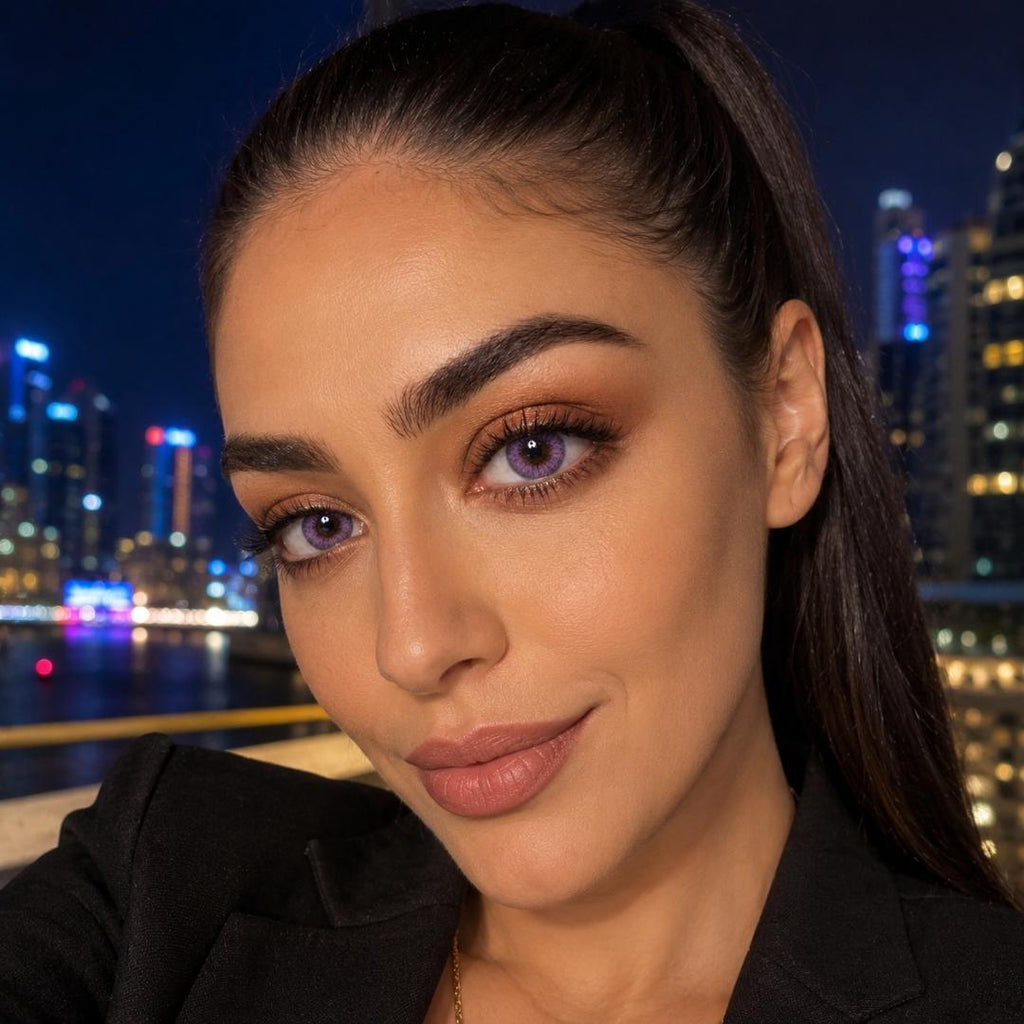 Woman with dark hair and makeup against a cityscape at night